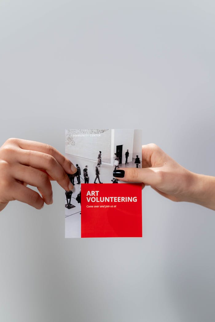our-services-2 Close-up of hands holding an art volunteering flyer against a neutral background.